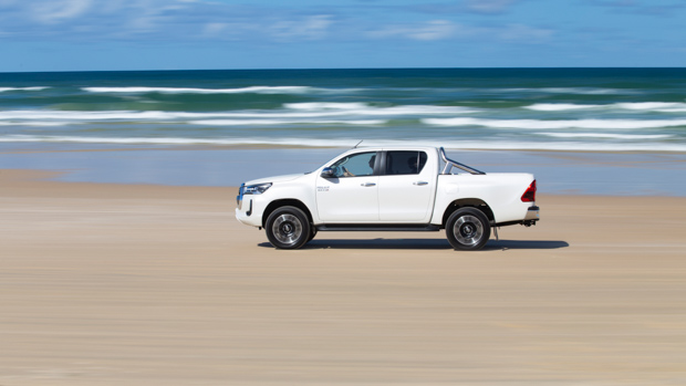 2022 Toyota Hilux SR5 review white ute - dynamic side profile beach shot #1