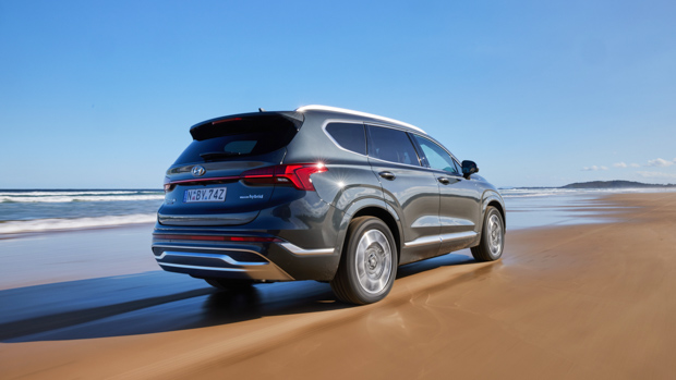 Hyundai Santa Fe Hybrid Highlander 2023 driving sand rear