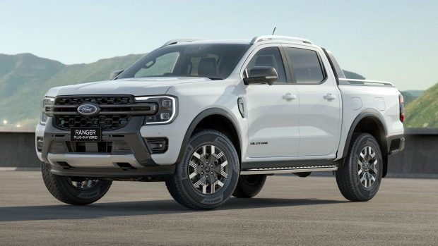 A Ford Ranger Wildtrak trail-in hybrid ute in white towards mountains and a blue sky